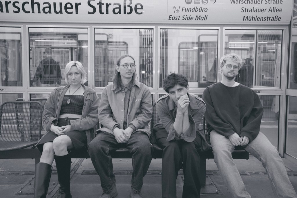 La band Dusk Saffron è seduta su una panchina. La foto è in bianco e nero